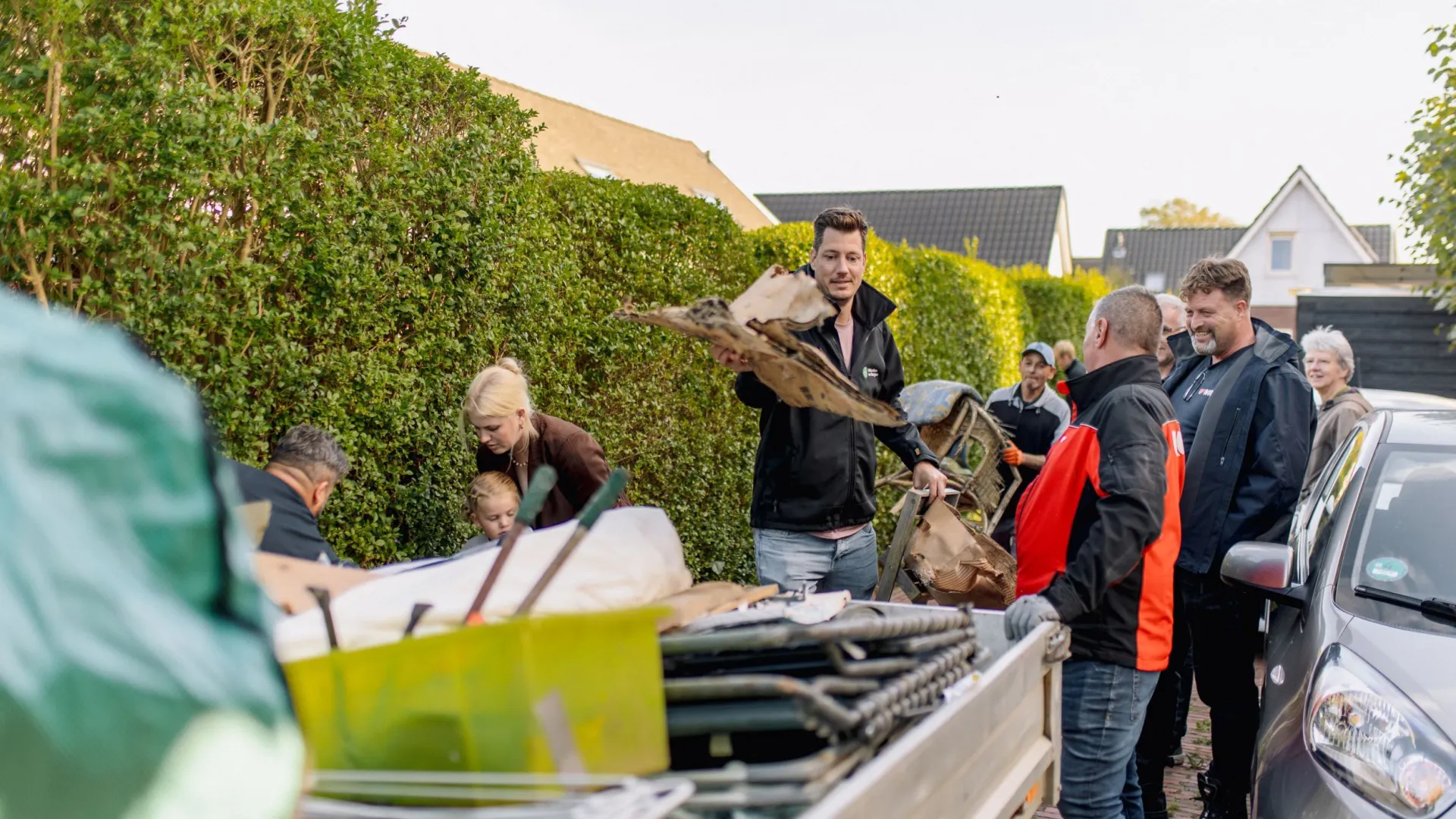 Mensen helpen bij het laden van afval in een aanhanger op straat.