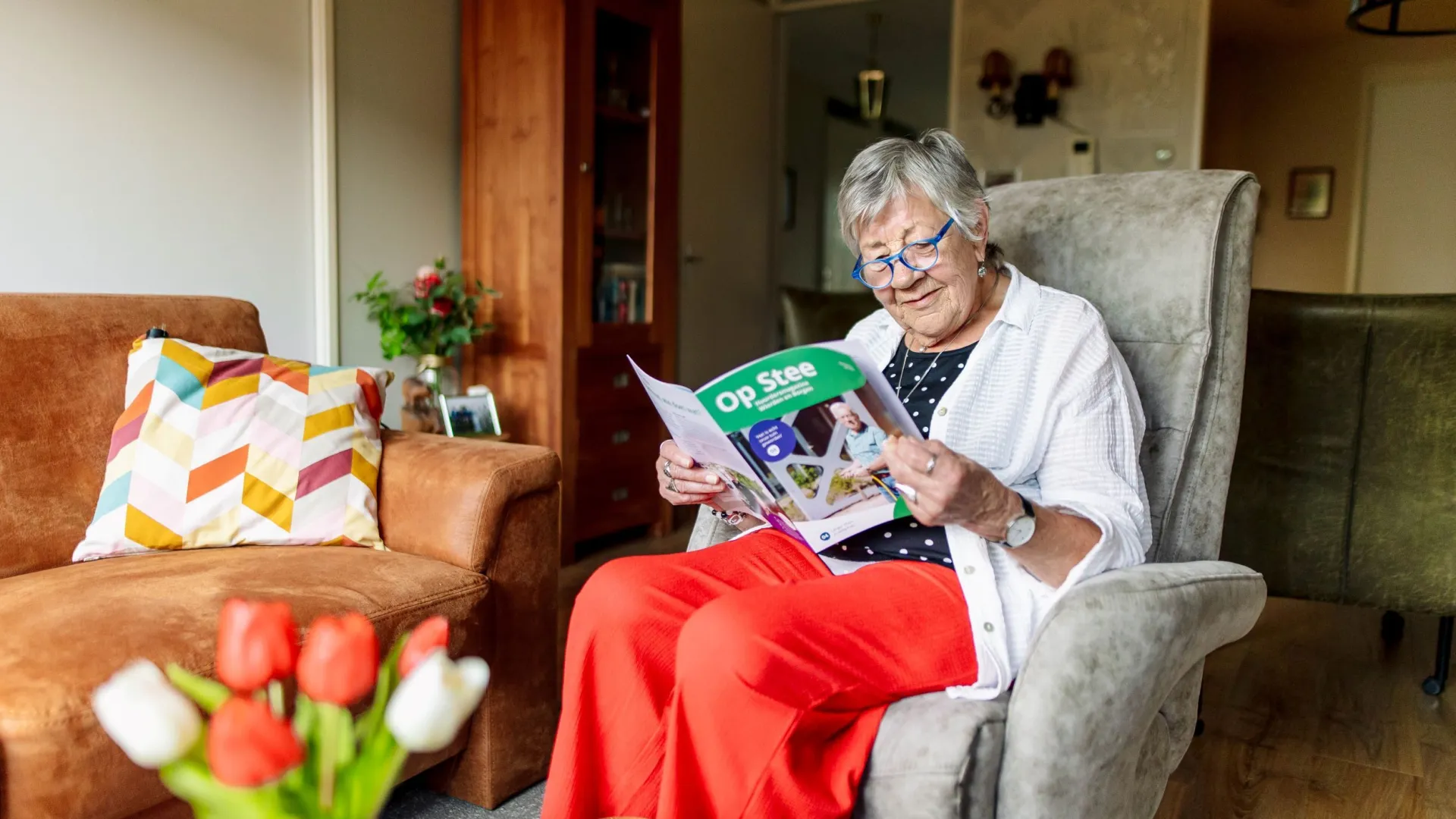 Vrouw leest een tijdschrift in een gezellige woonkamer.