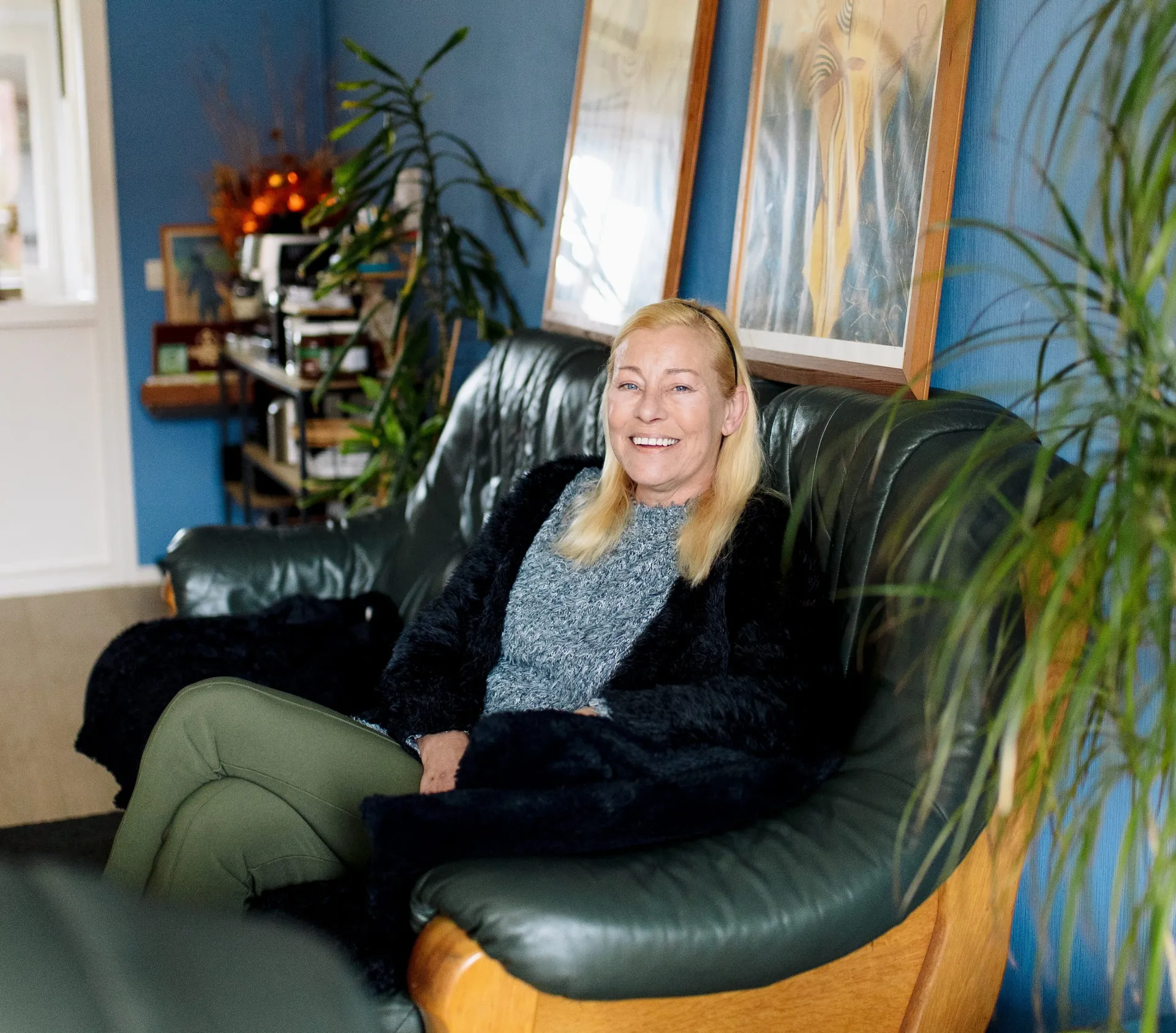 Lea zit ontspannen op een bank in een gezellig ingerichte kamer.