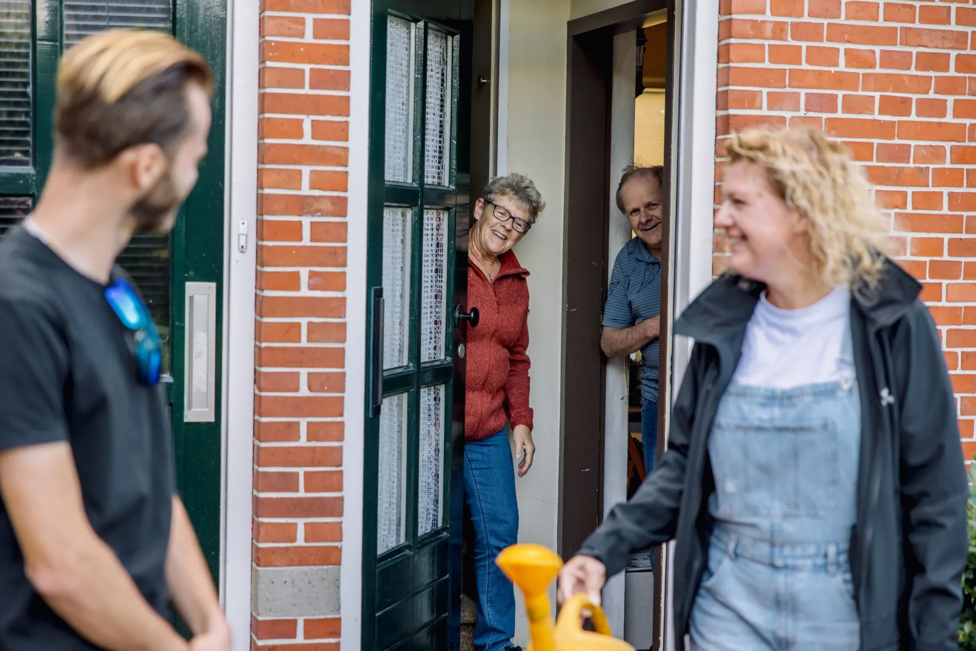 Mensen begroeten elkaar bij een deur van een huis.