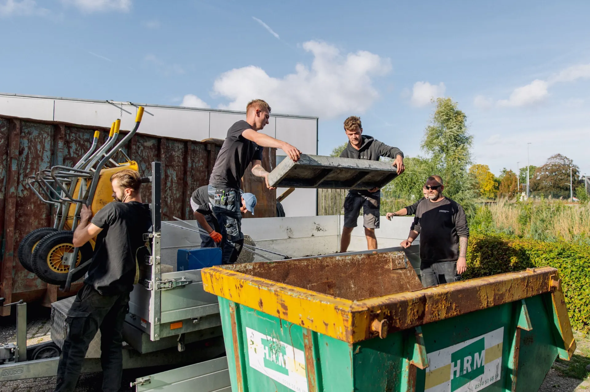 Mensen laden een container met bouwmaterialen uit.