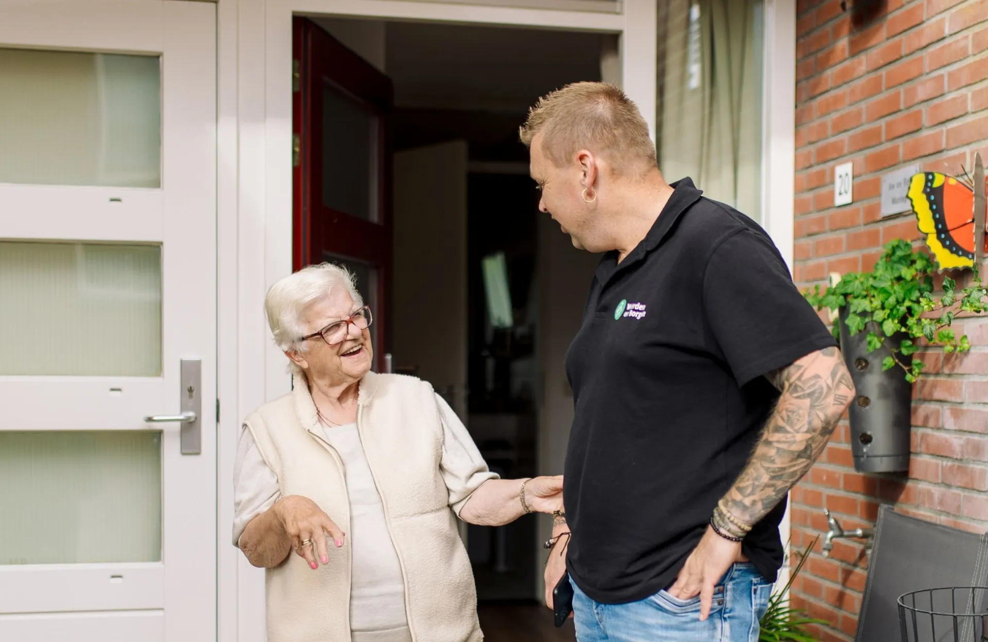 Wijkbeheerder in gesprek met huurder bij voordeur